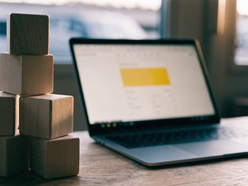 Holz-Bausteine neben einem Laptop mit Website-Layout – Baukasten oder Profi